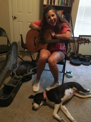 a picture of a happy guitar student in Brad Barnes Guitar Studio with Brad's puppy dog laying at her feet